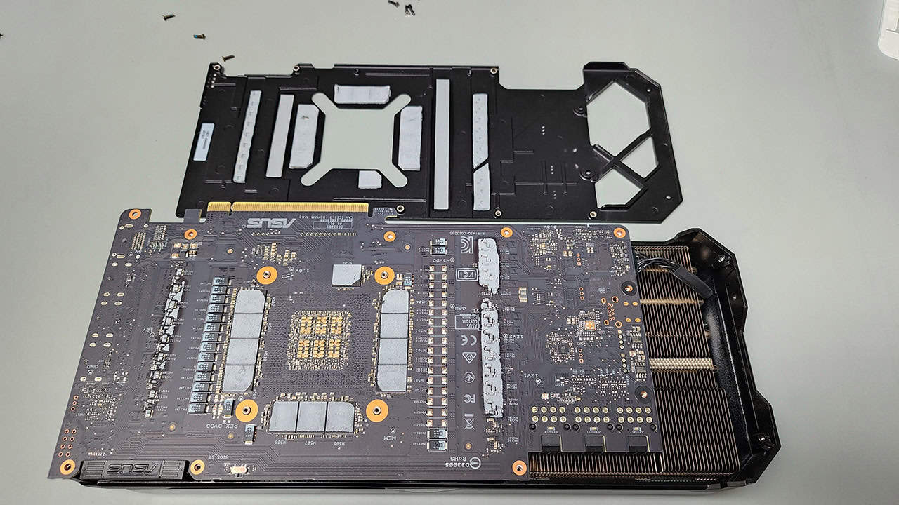 ASUS graphics card with the backplate and bracket removed, showing the circuit board, memory chips, and gray thermal pads.