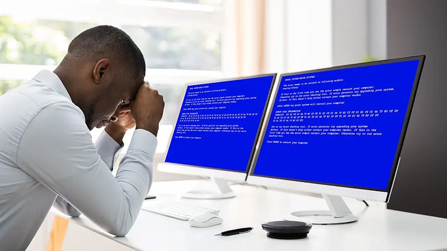 A businessman is experiencing a blue screen of death, slumped over.