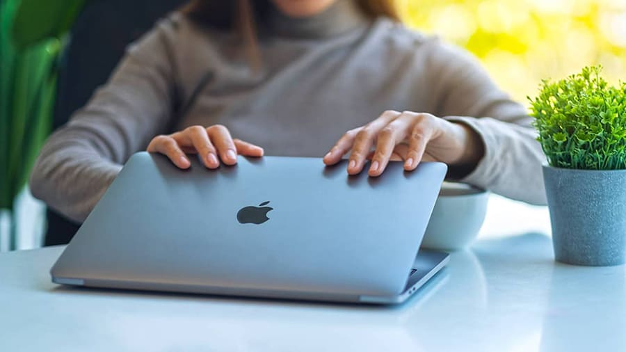 A woman is opening the lid on a MacBook Pro.