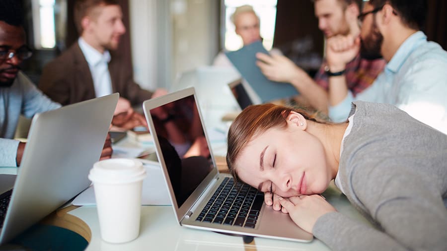 Young woman sleeping with her head on office desk.