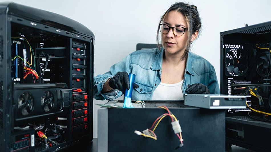 A woman is inspecting and cleaning a computer.