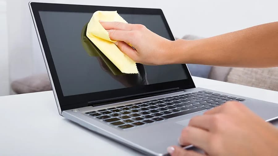 Cleaning a MacBook's screen with a microfiber cloth.