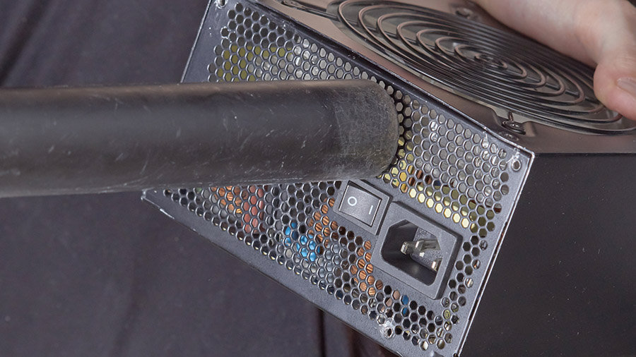 Someone uses a vacuum cleaner to suck out the dust inside a computer PSU.