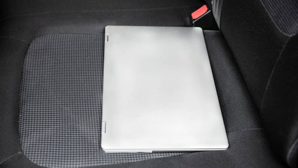 A laptop is placed on a car's front seat.
