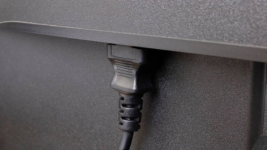 An IEC power plug is plugged into the back of a monitor.