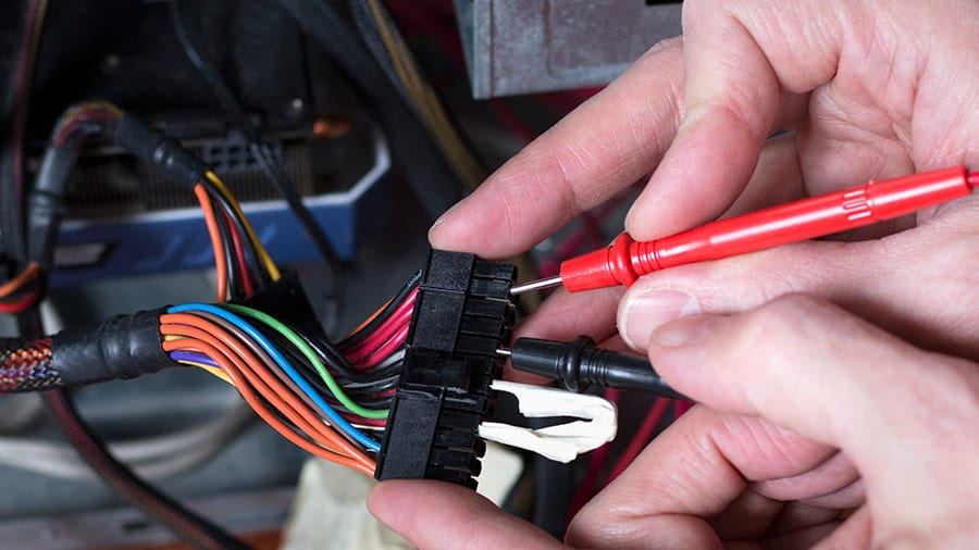 Someone is testing the outputs of a computer power supply using a multimeter.