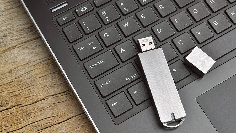 A Windows installation USB flash drive is placed on a computer's keyboard.