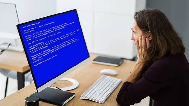 A woman in front of a computer with a blue screen.