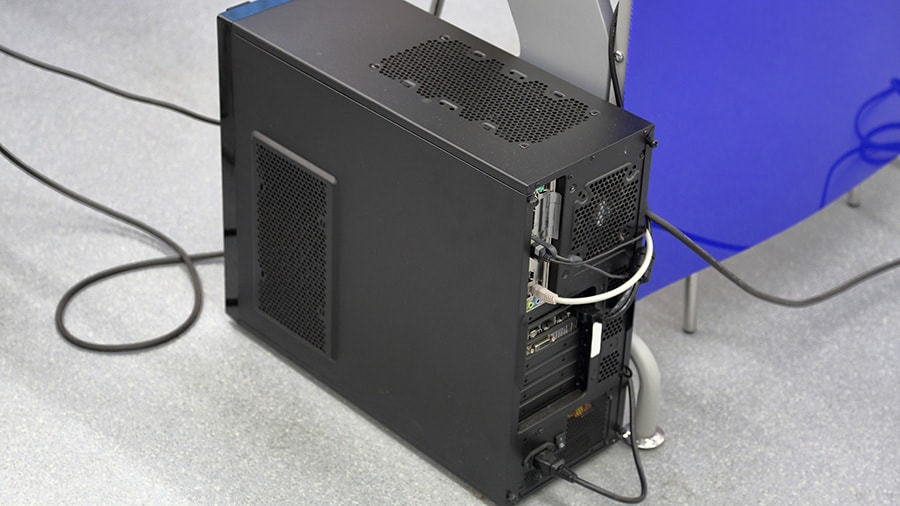 A computer that is placed on the floor of a home office.